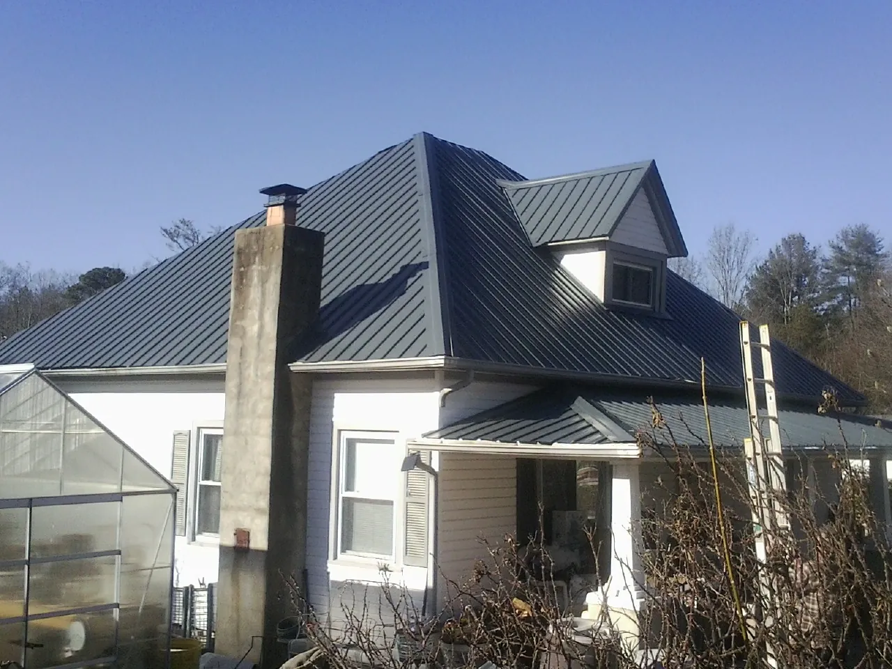 Dark blue standing seam metal roof on a white farmhouse with dormer — Slate & Tile Roof Repair by Roofing Brothers in Essex Junction