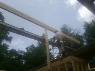 Carpenter setting a ridge beam over a new addition frame — Ice Dam Removal by Roofing Brothers in Essex Junction
