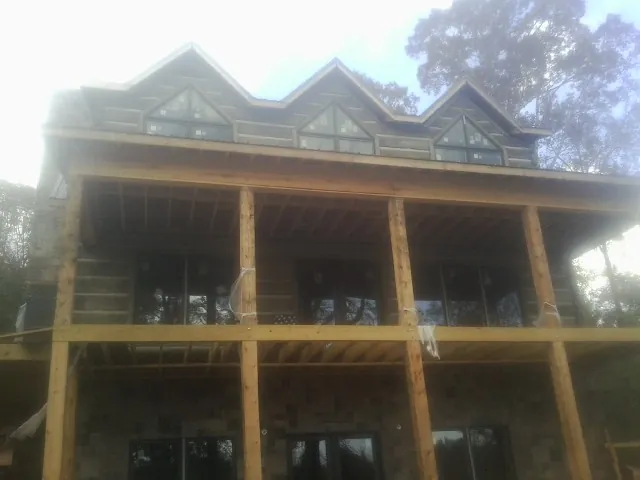 Dormers and porch framing on a large log home under construction — Roof Coating work by our crew in Essex Junction