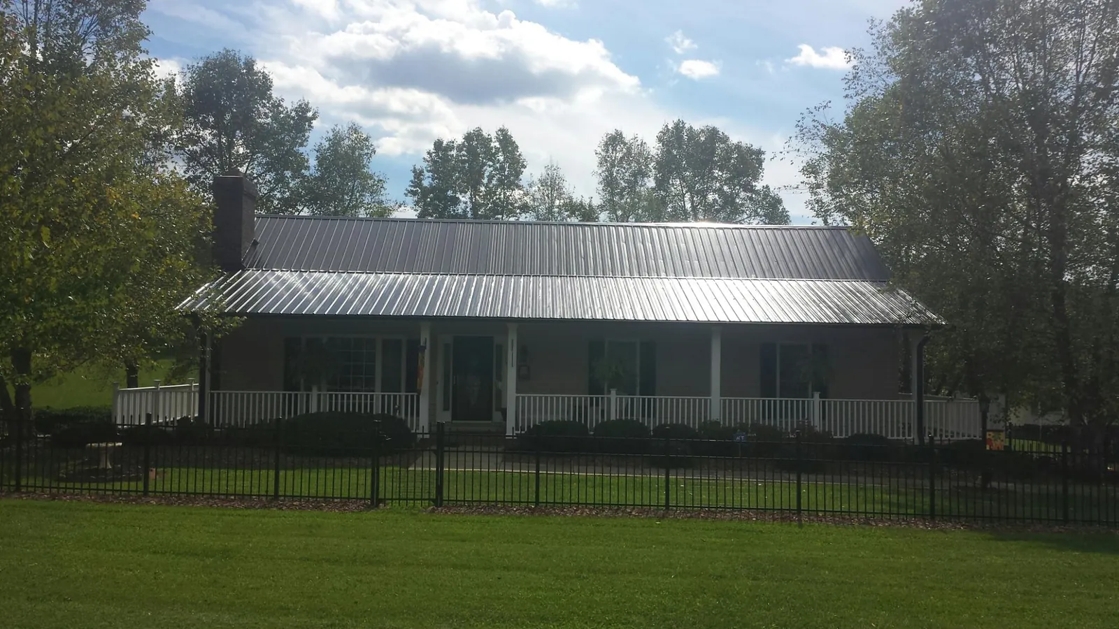 Gray metal roof on a brick ranch with a full width front porch — Gutter Guard Installation work by our crew in Essex Junction