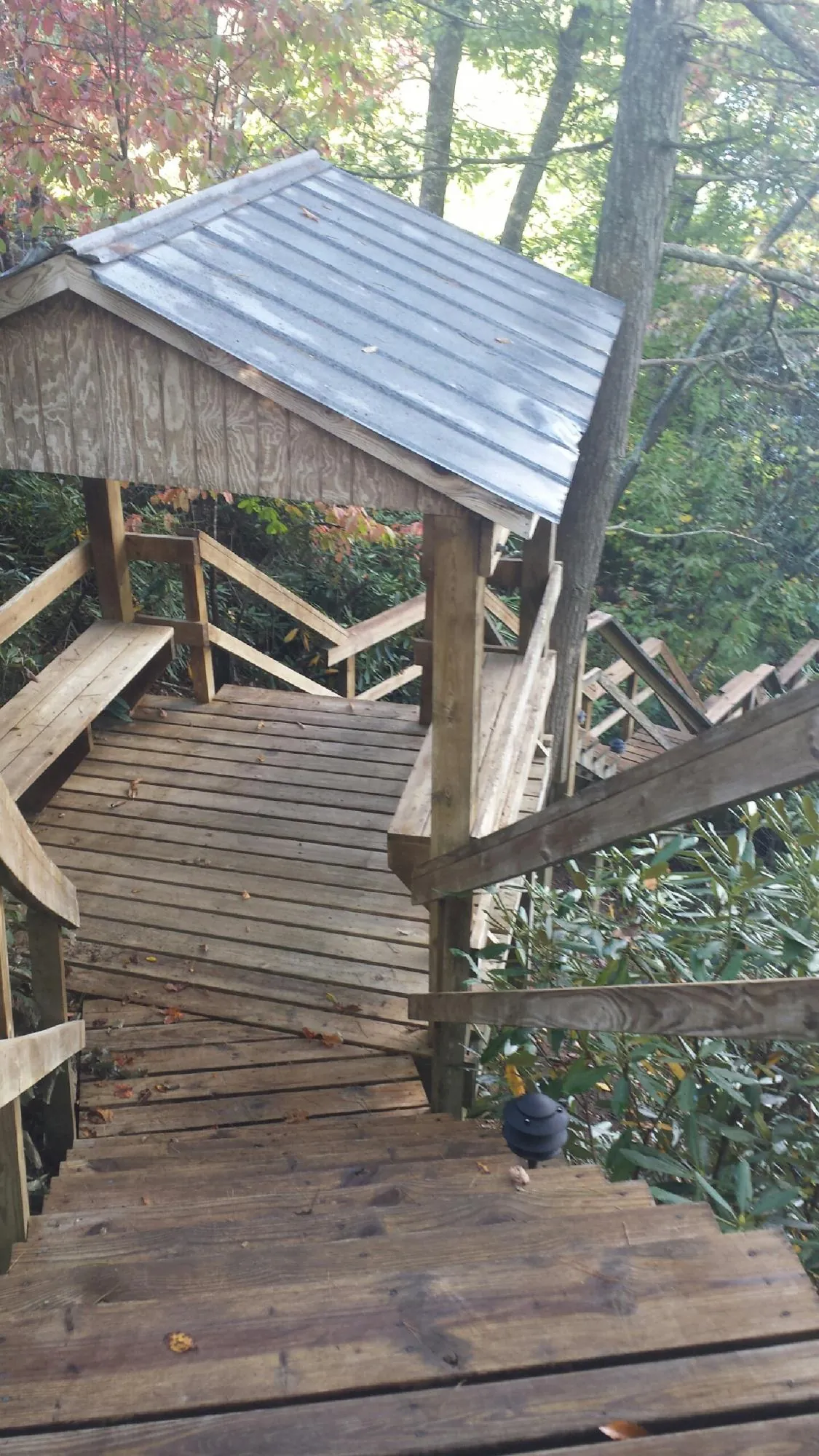 Metal roofed shelter over wooden steps on a wooded walkway — Skylight Repair & Installation work by our crew in Essex Junction