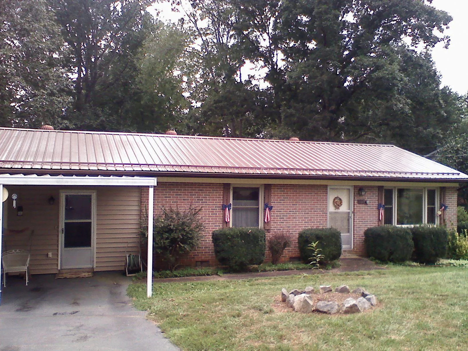 Bronze metal roof and carport on a brick ranch home — Roof Repair work by our crew in Essex Junction