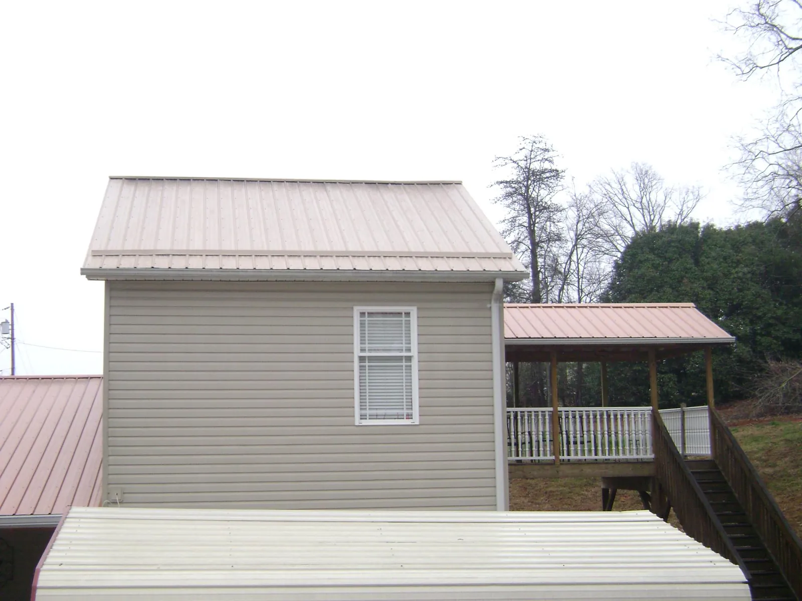 Tan metal roofs on a two story addition and attached porch, from a Roof Replacement job in Essex Junction
